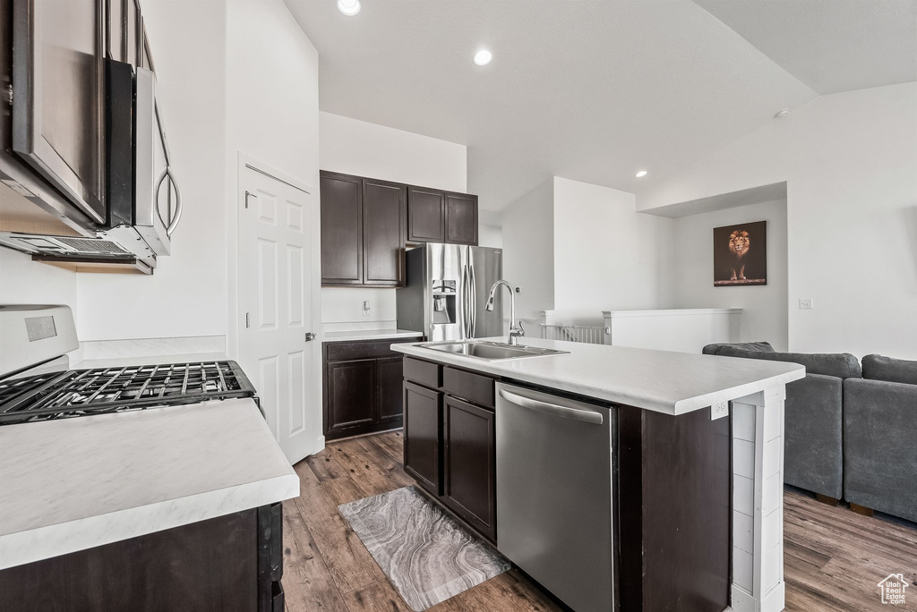 Kitchen featuring dark brown cabinets, dark hardwood / wood-style floors, lofted ceiling, stainless steel appliances, and a center island with sink