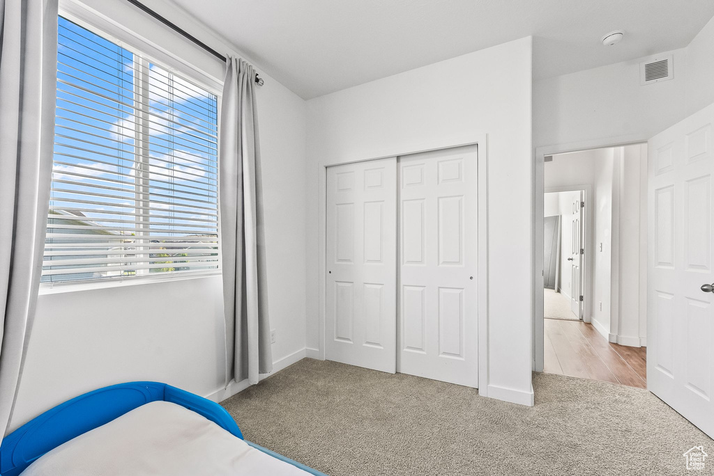 Bedroom with a closet, multiple windows, and light colored carpet