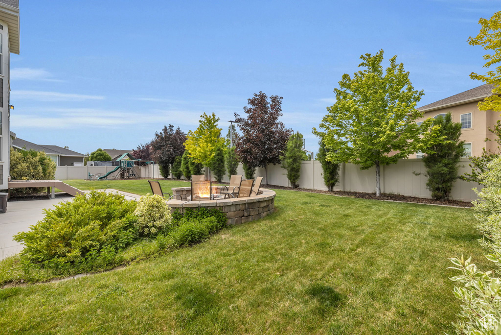 View of yard featuring a playground and an outdoor fire pit