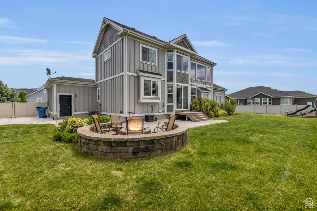 Back of property with a patio, a playground, a fire pit, and a yard