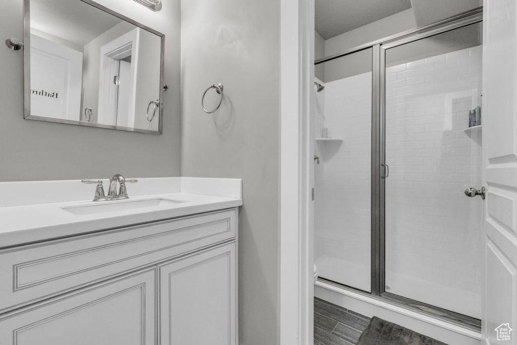 Bathroom with a shower with shower door, vanity, and toilet