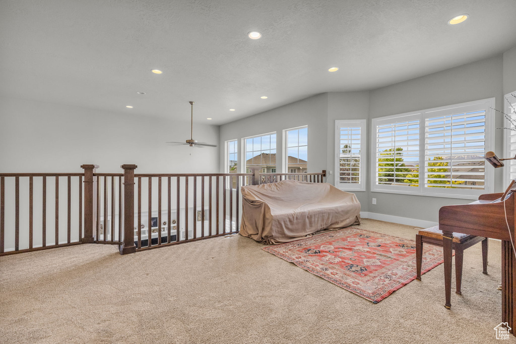 Carpeted living room with plenty of natural light and ceiling fan