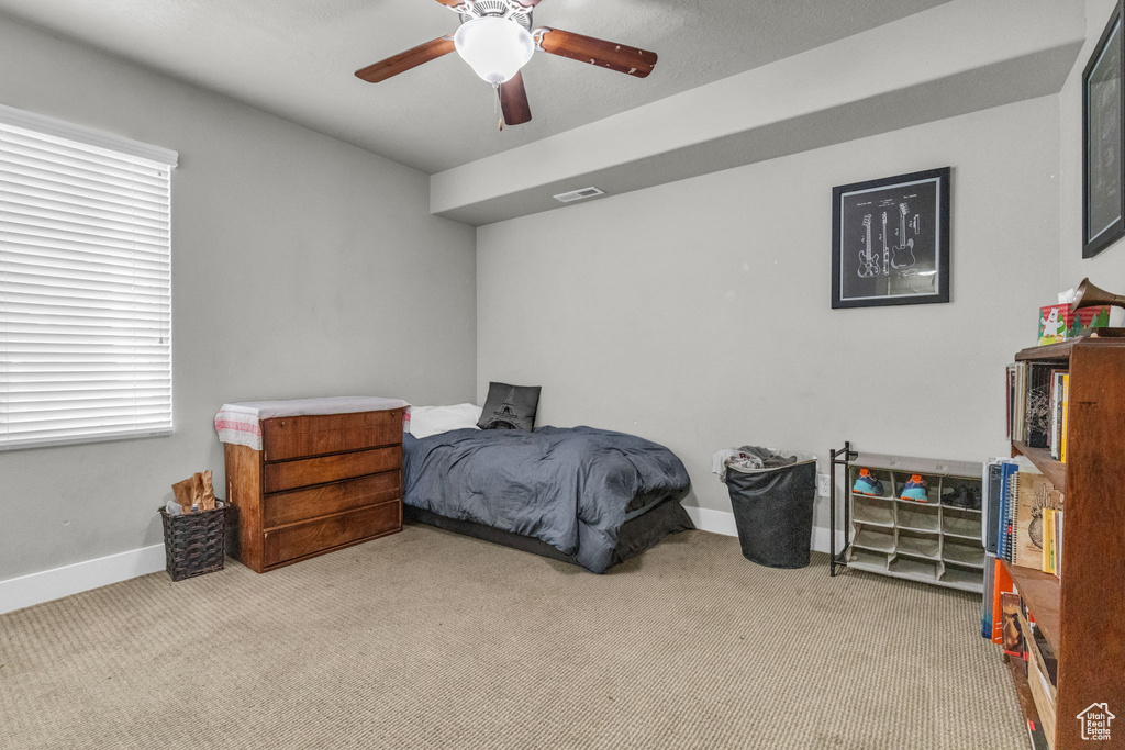 Carpeted bedroom featuring ceiling fan and multiple windows