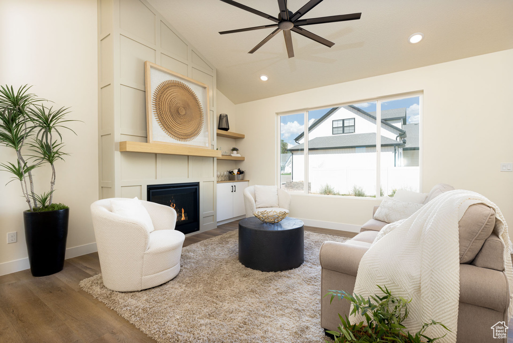 Living room with ceiling fan, a fireplace, lofted ceiling, and light wood-type flooring