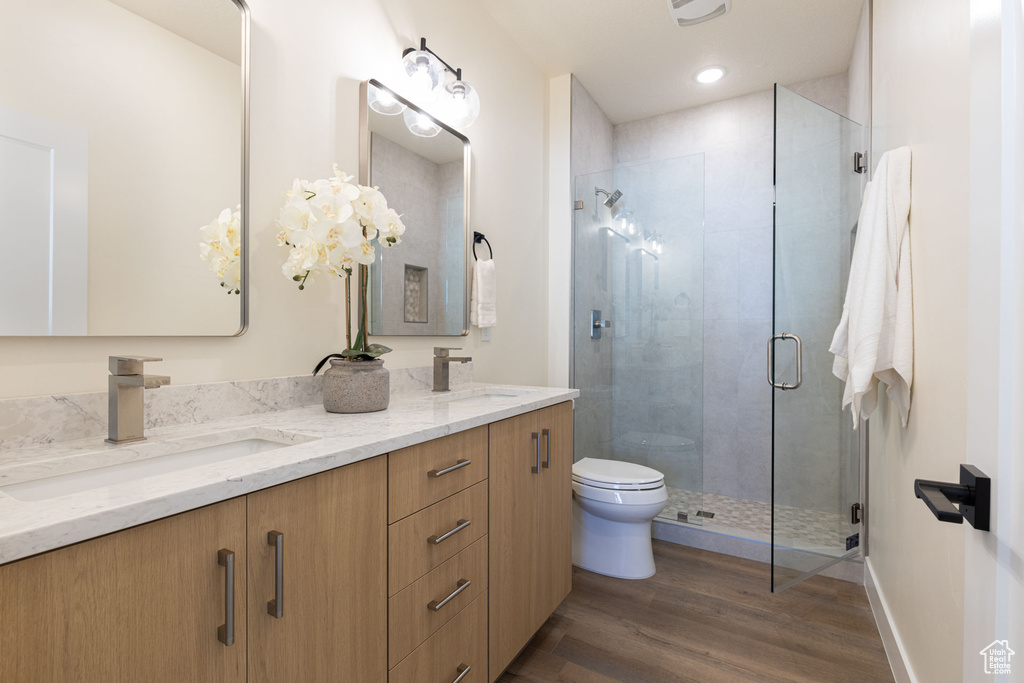 Bathroom with a shower with shower door, toilet, vanity, and wood-type flooring