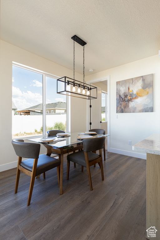 Dining space featuring a textured ceiling, an inviting chandelier, and dark wood-type flooring