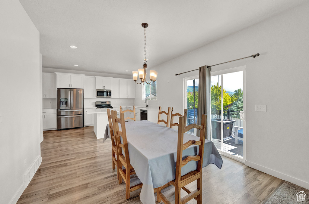 Dining space featuring sink, light wood-type flooring, and an inviting chandelier