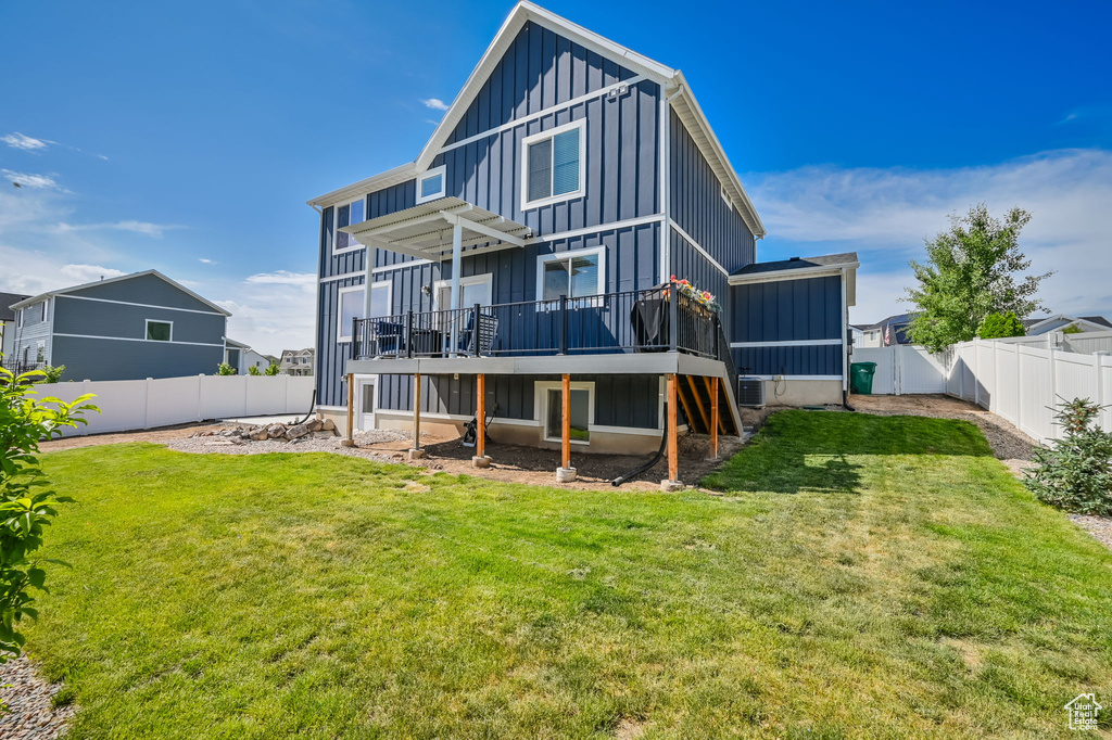 Rear view of property with a deck and a lawn