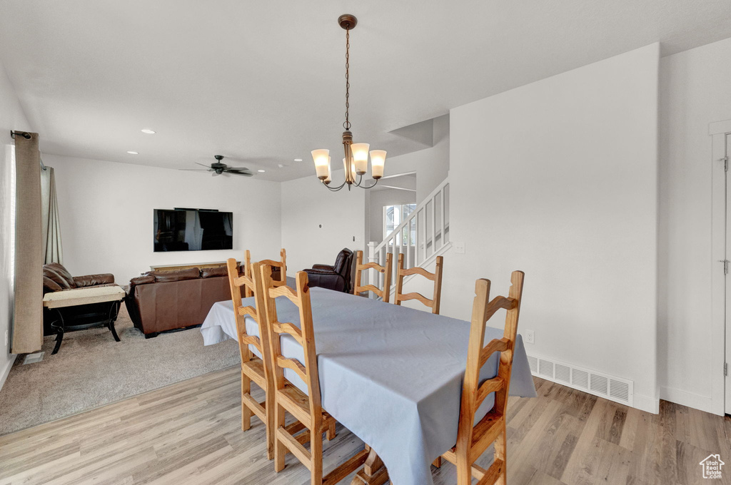 Dining area featuring ceiling fan with notable chandelier and light wood-type flooring