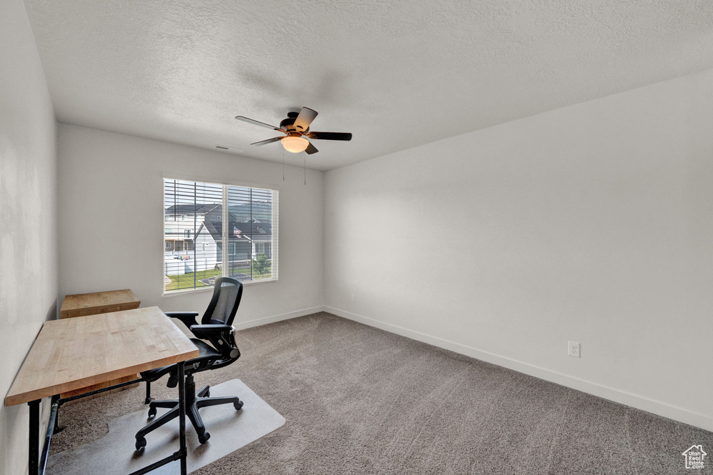 Office with a textured ceiling, carpet floors, and ceiling fan