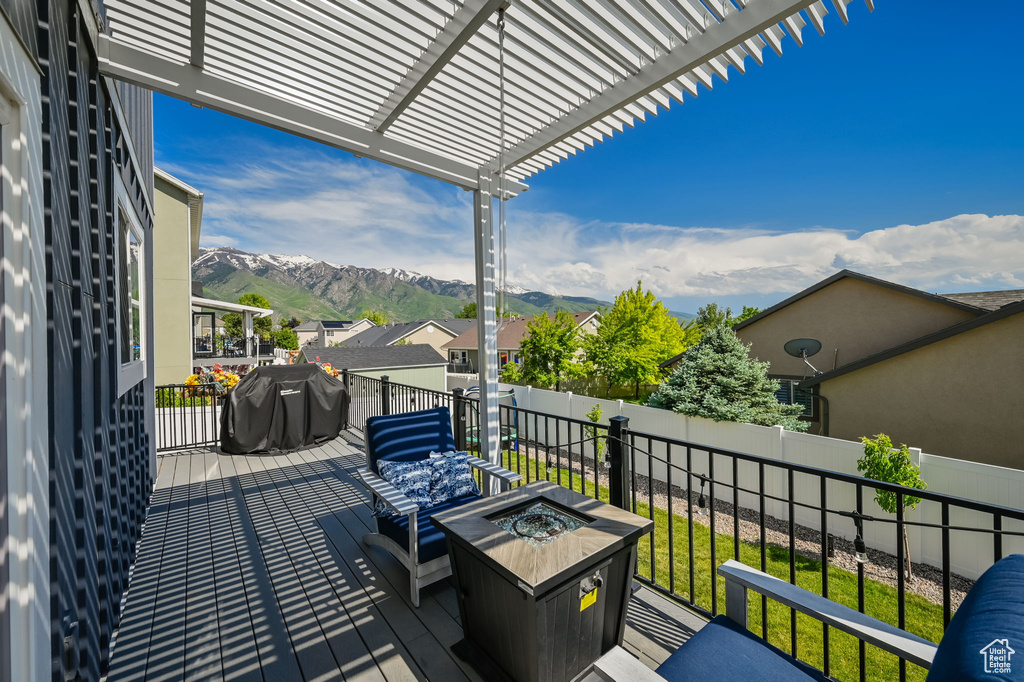 Wooden deck featuring a pergola, a mountain view, an outdoor living space with a fire pit, and grilling area