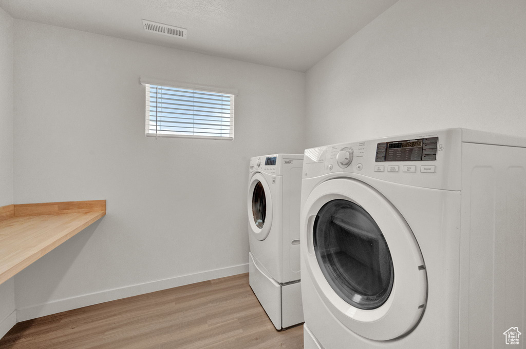 Laundry area with washer and dryer and light wood-type flooring