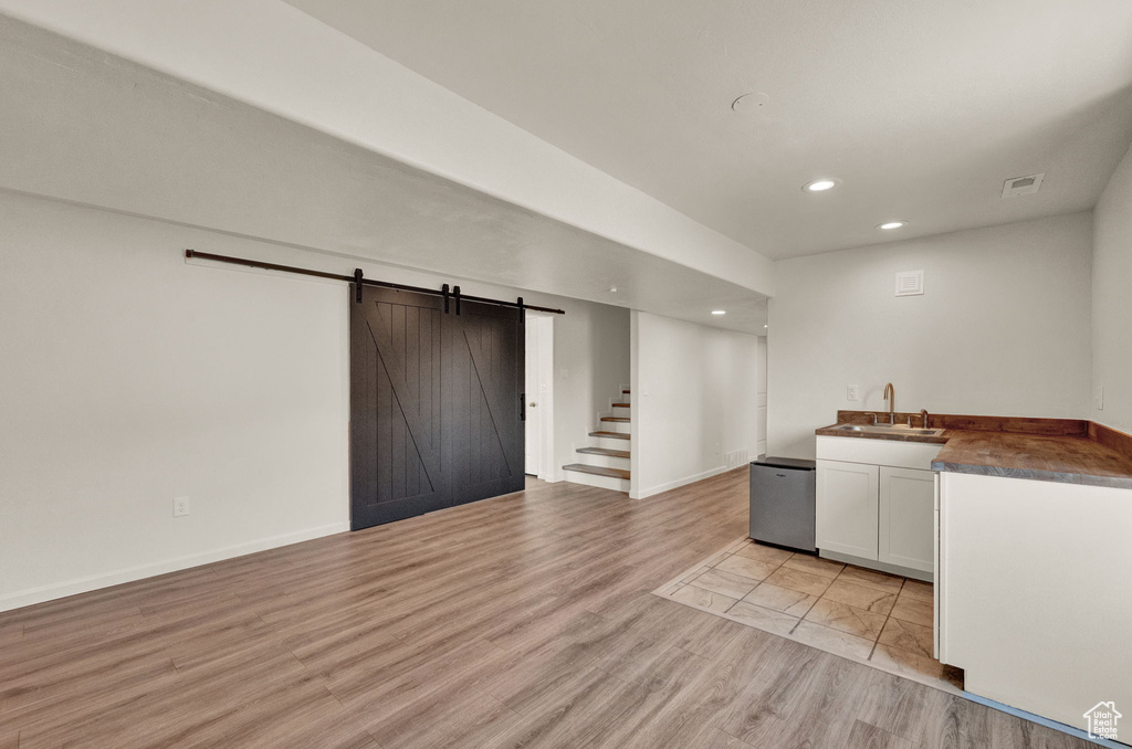 Kitchen with dishwasher, white cabinetry, a barn door, sink, and light tile floors