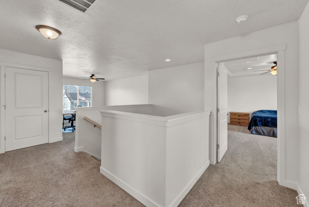 Hall featuring a textured ceiling and light colored carpet