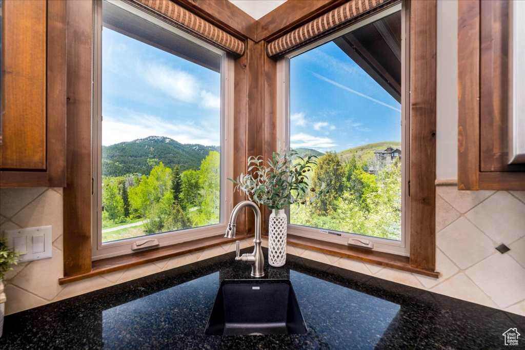 Interior details featuring sink, backsplash, and dark stone countertops