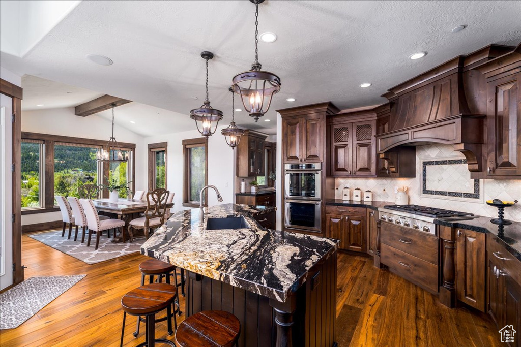 Kitchen with sink, dark hardwood / wood-style flooring, appliances with stainless steel finishes, and a kitchen island with sink