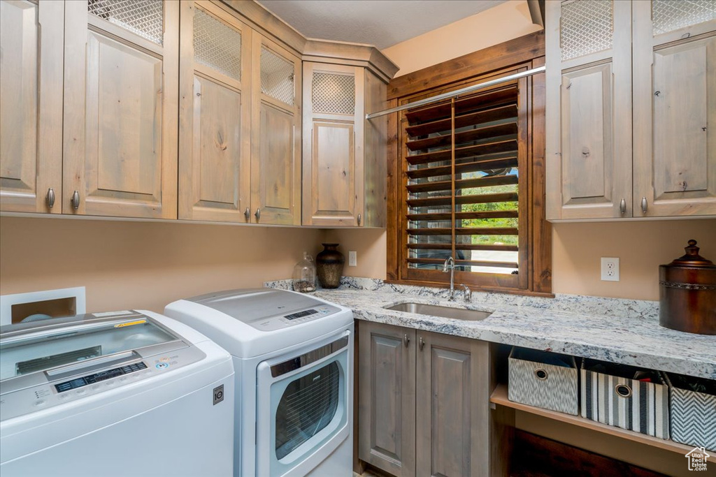 Clothes washing area with sink, washing machine and clothes dryer, hookup for a washing machine, and cabinets