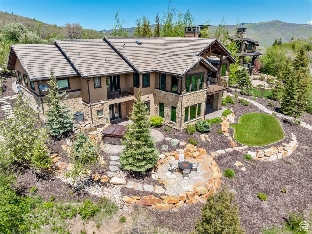 Rear view of property featuring an outdoor fire pit, a mountain view, a balcony, and a patio