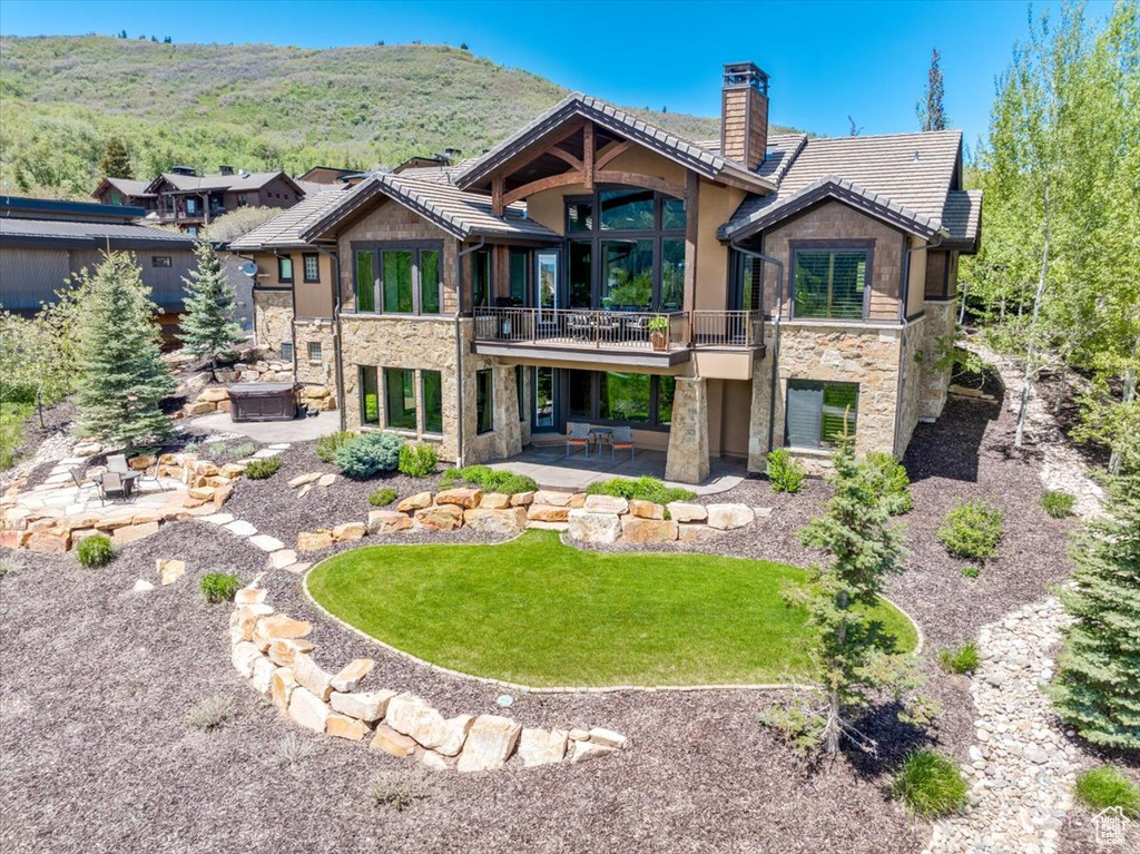 Back of property featuring a patio, a mountain view, and a yard