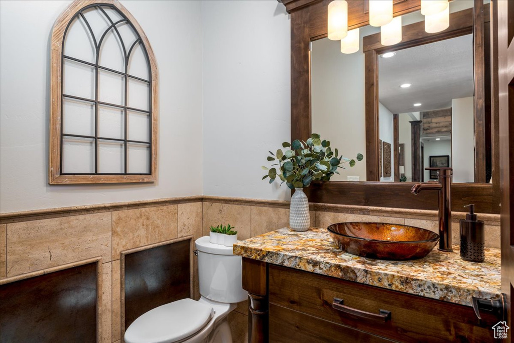 Bathroom with vanity with extensive cabinet space, tile walls, and toilet