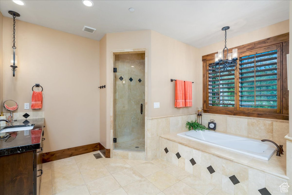 Bathroom featuring shower with separate bathtub, vanity, and tile floors