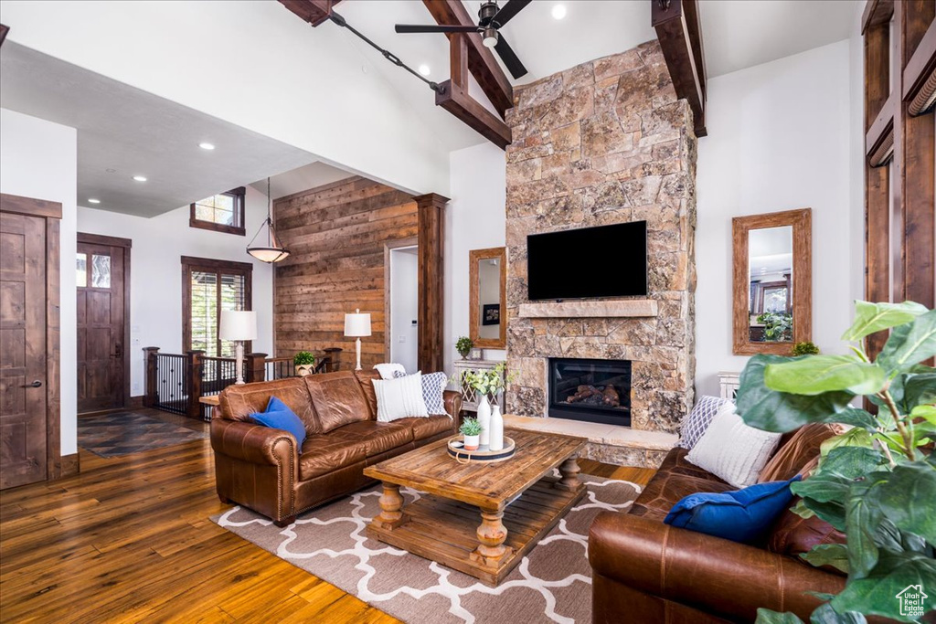 Tiled living room with ceiling fan, ornate columns, beamed ceiling, a fireplace, and high vaulted ceiling