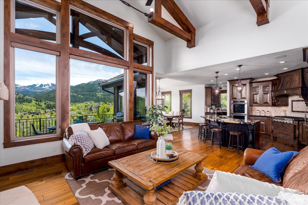 Living room with a mountain view, beamed ceiling, hardwood / wood-style floors, a high ceiling, and sink