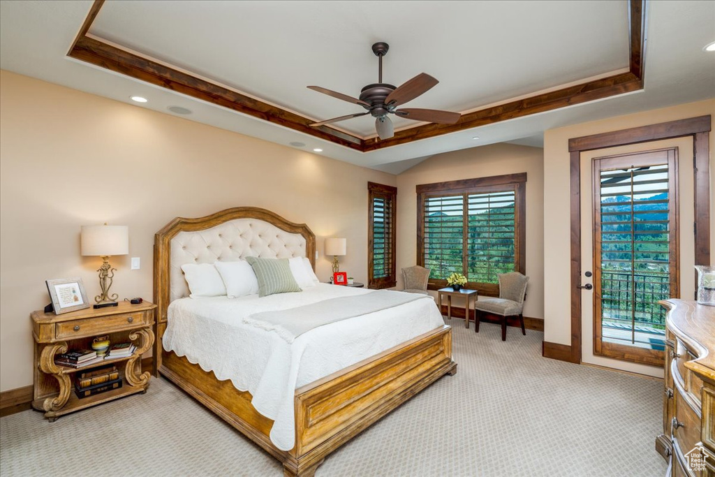 Carpeted bedroom with access to outside, a tray ceiling, and ceiling fan