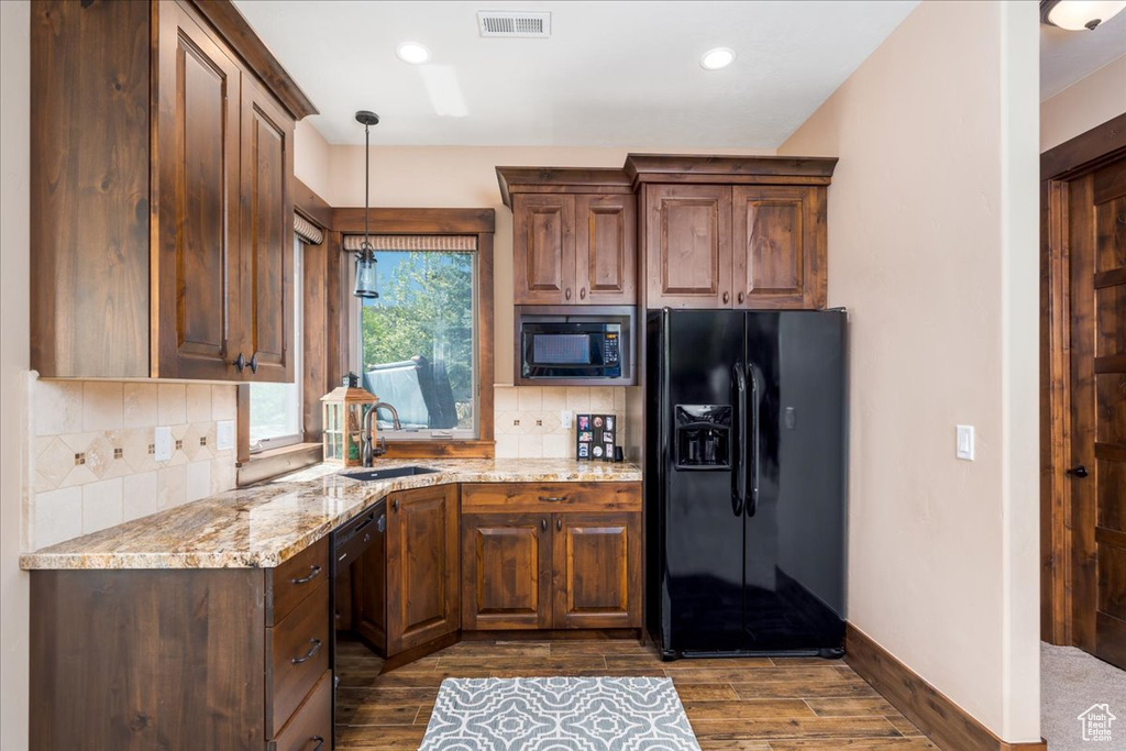 Kitchen featuring black appliances, backsplash, dark hardwood / wood-style floors, and light stone counters