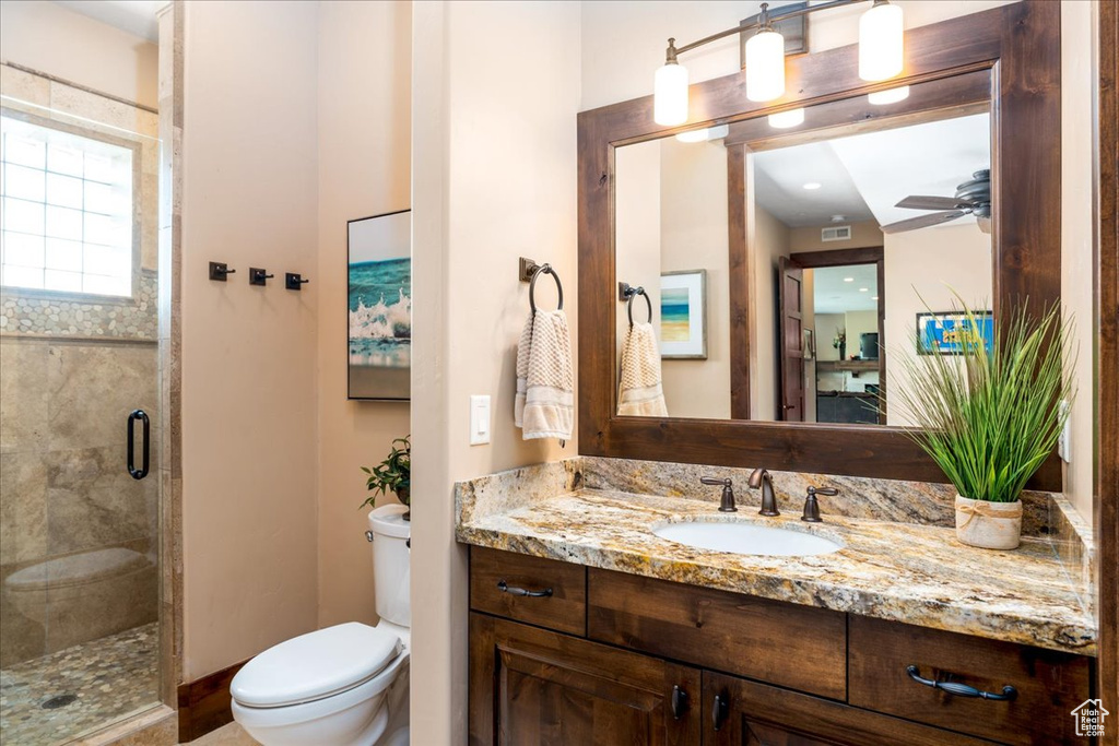 Bathroom featuring ceiling fan, an enclosed shower, toilet, and vanity