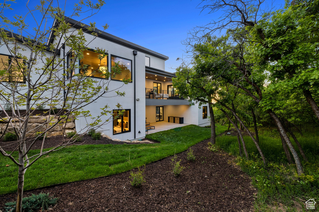 Rear view of property featuring a patio, a yard, and a balcony