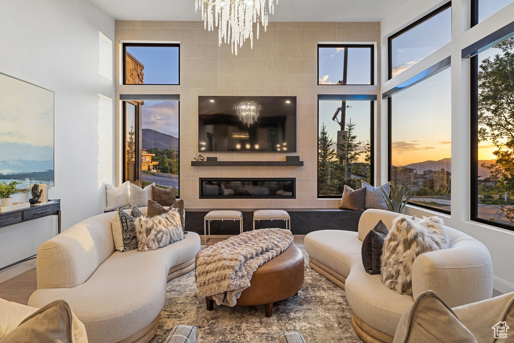 Living room with a towering ceiling, a large fireplace, a chandelier, and hardwood / wood-style floors