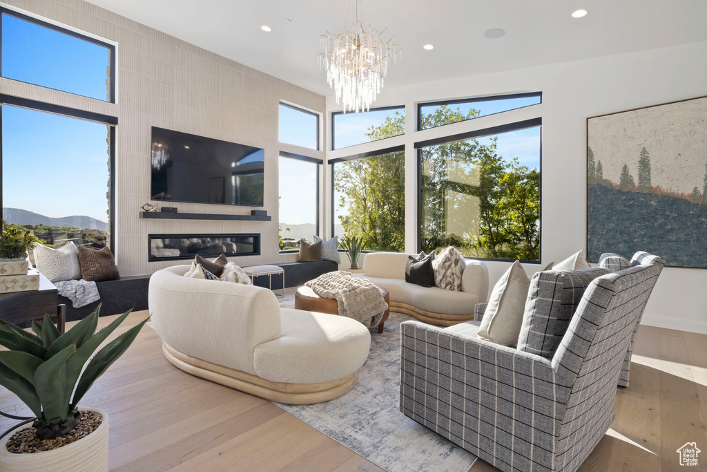 Living room with a high ceiling, a large fireplace, hardwood / wood-style flooring, and a chandelier