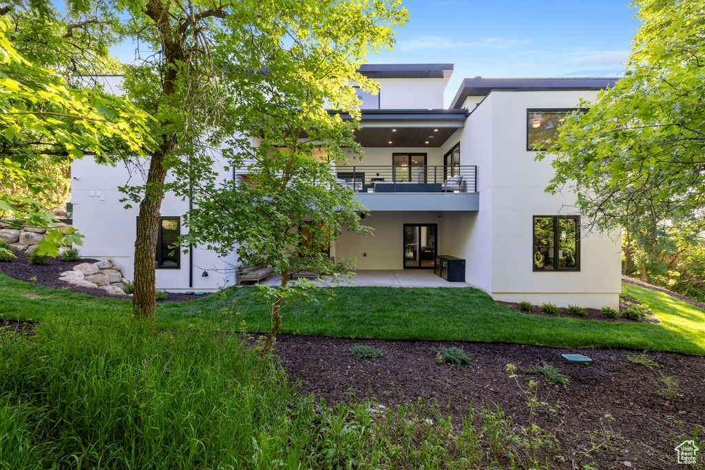 Back of house with a balcony and a yard