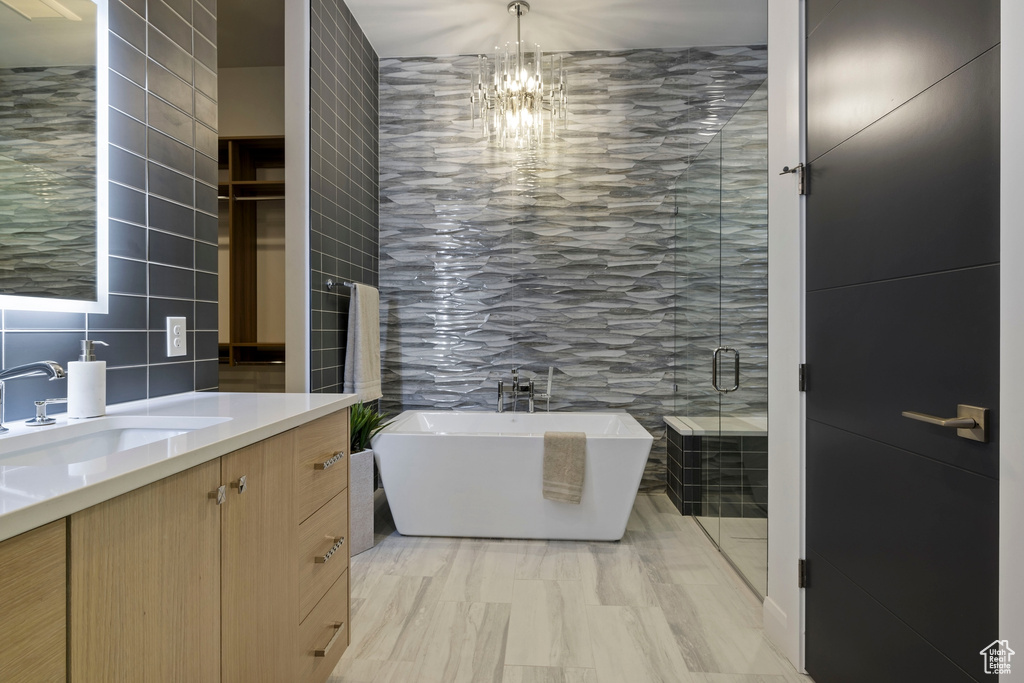 Bathroom featuring tile floors, an inviting chandelier, vanity, and tile walls