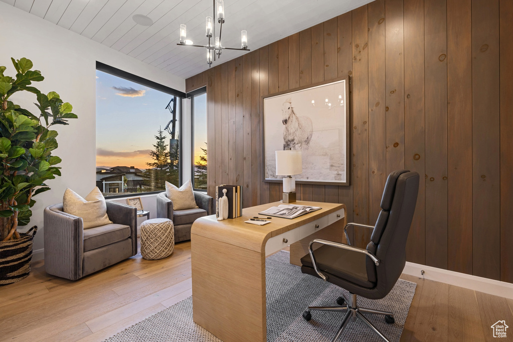 Office featuring light hardwood / wood-style floors, a chandelier, and wood walls