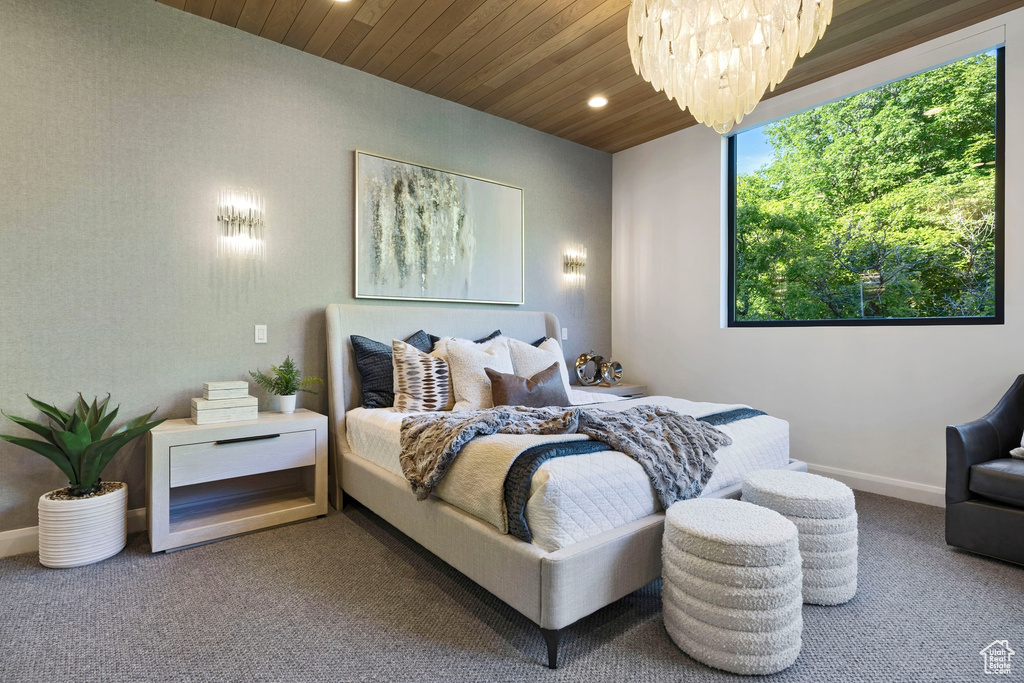 Carpeted bedroom featuring wooden ceiling, multiple windows, and a chandelier