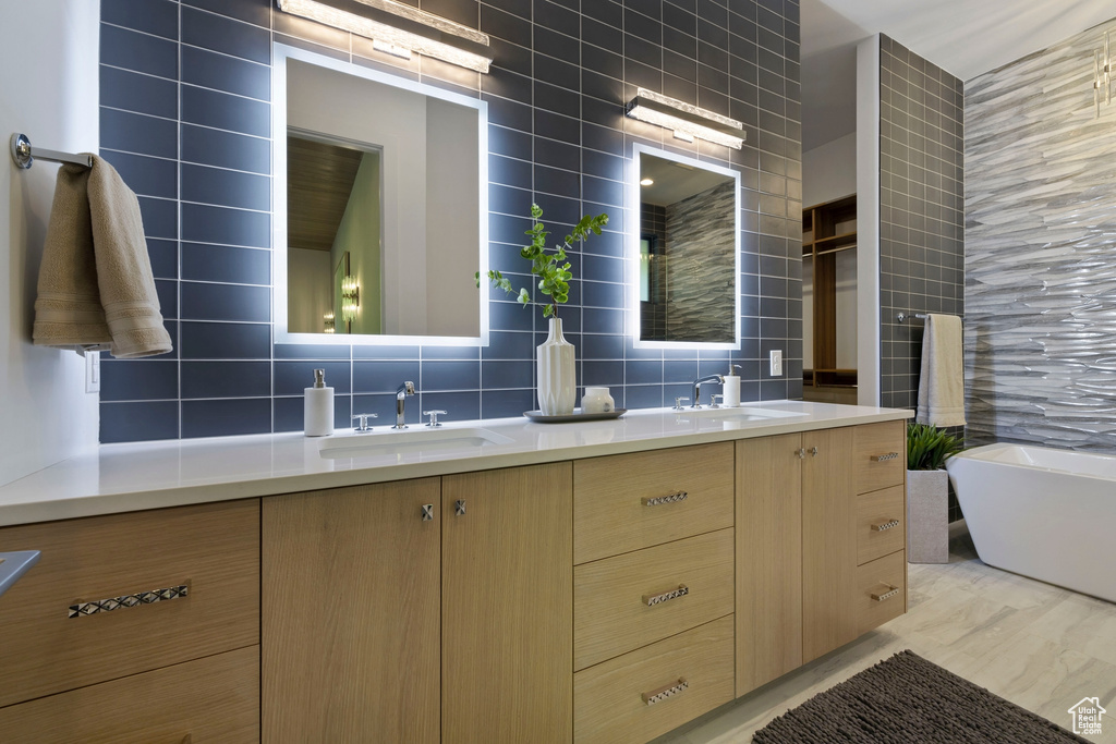 Bathroom featuring tile walls, backsplash, double sink vanity, and hardwood / wood-style floors