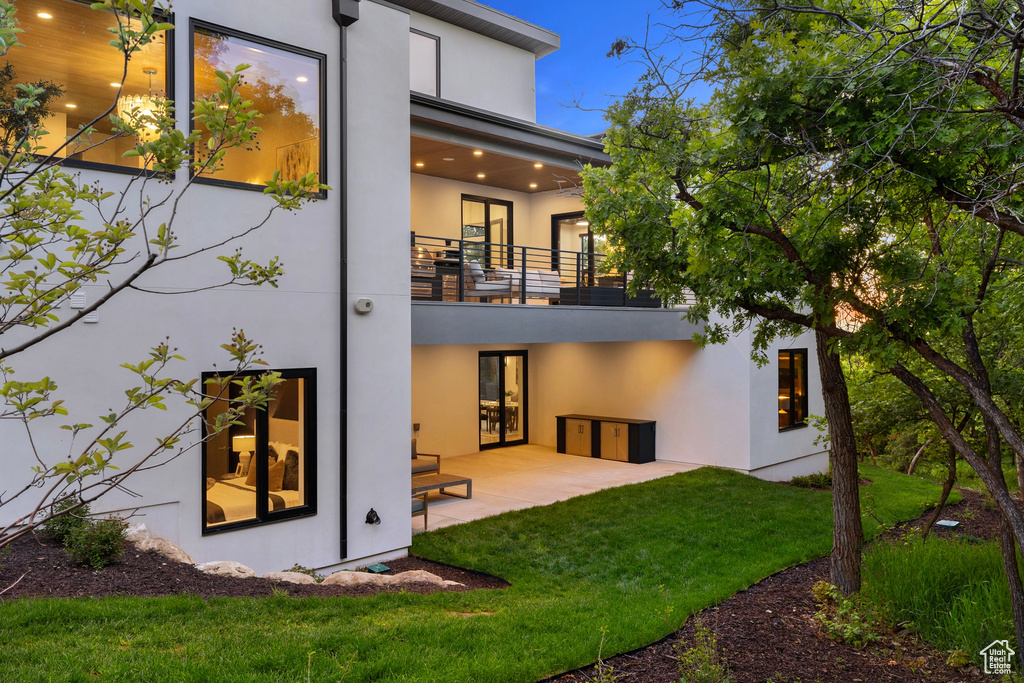 Rear view of house with a patio area, a balcony, and a lawn