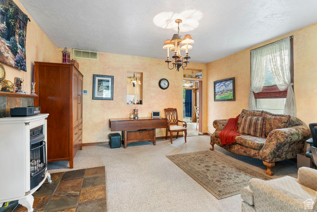 Living room featuring an inviting chandelier, a textured ceiling, and carpet floors