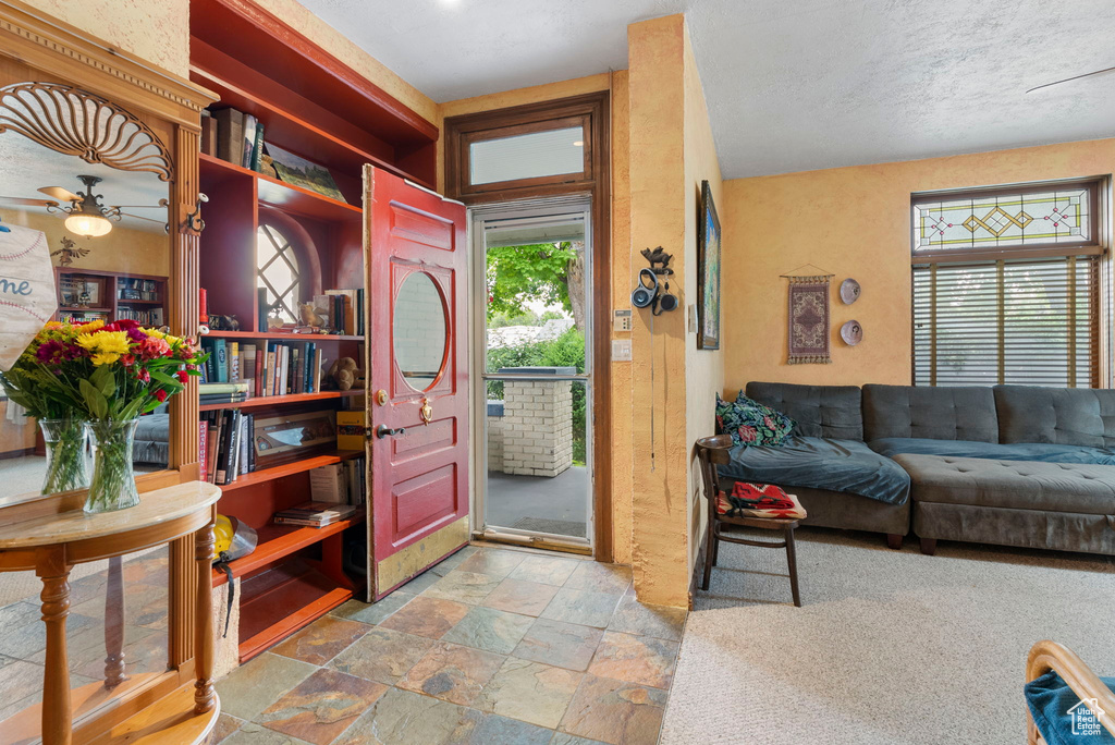 Living room with tile floors, a textured ceiling, and ceiling fan