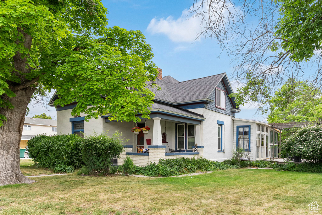 View of front of house with covered porch and a front lawn