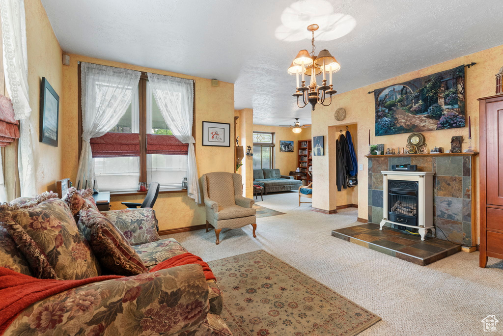 Living room featuring carpet flooring, an inviting chandelier, a tiled fireplace, and a textured ceiling