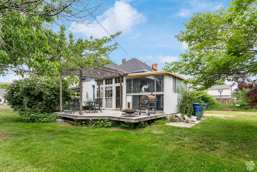 Rear view of house featuring a pergola, a lawn, and a deck