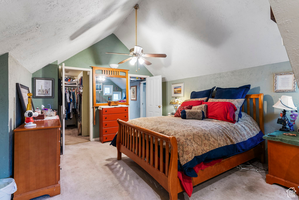 Carpeted bedroom with ceiling fan, a closet, a spacious closet, a textured ceiling, and lofted ceiling