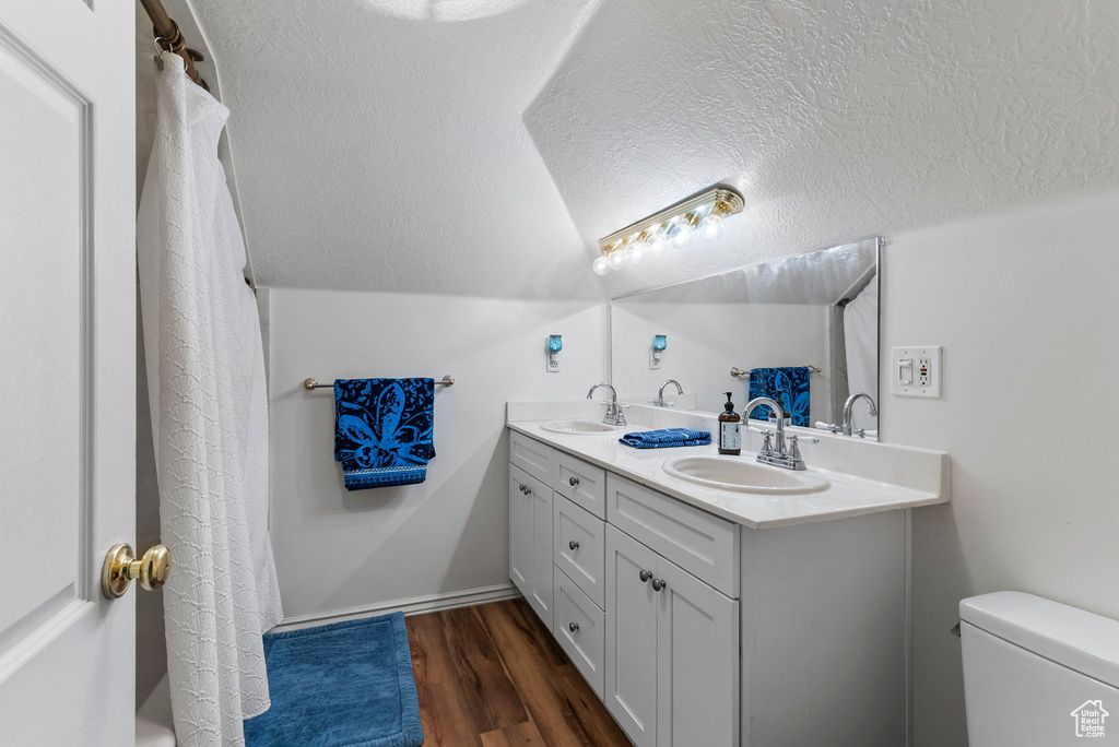 Bathroom with a textured ceiling, toilet, double sink vanity, and hardwood / wood-style floors