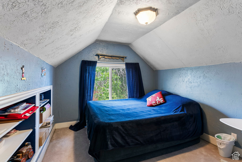 Bedroom featuring carpet, a textured ceiling, and lofted ceiling