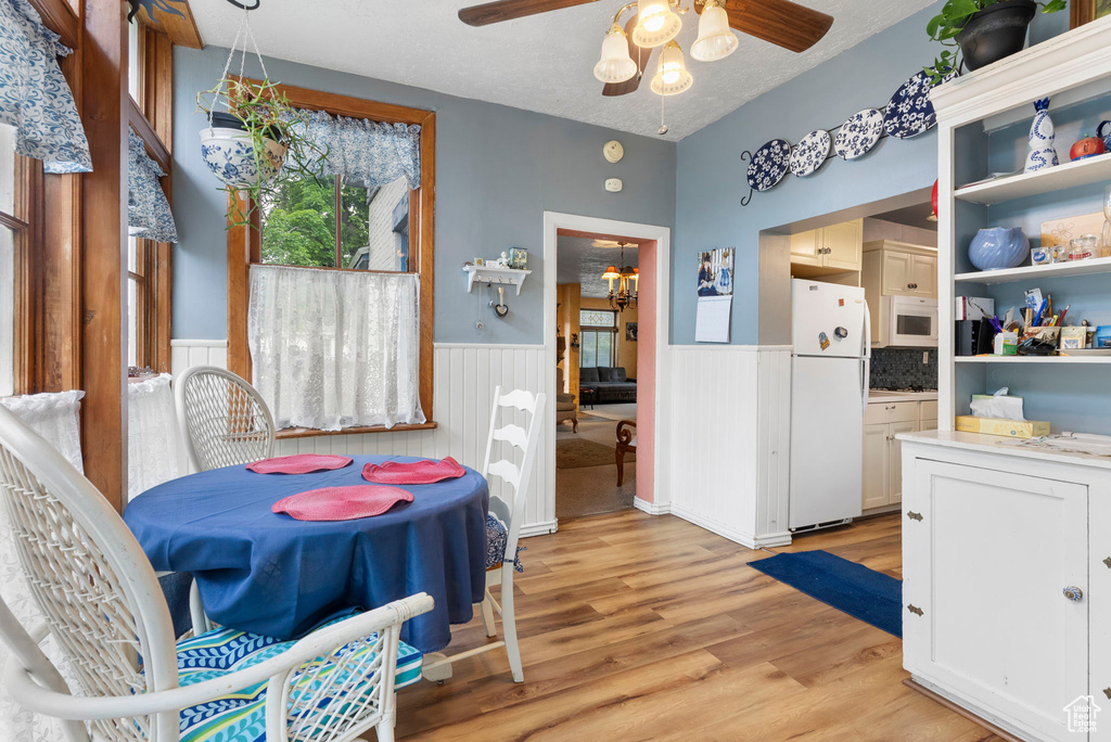 Dining area with ceiling fan with notable chandelier and light wood-type flooring