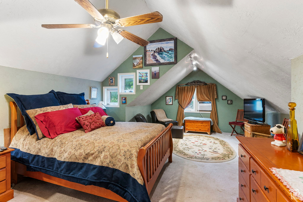 Carpeted bedroom featuring ceiling fan and vaulted ceiling