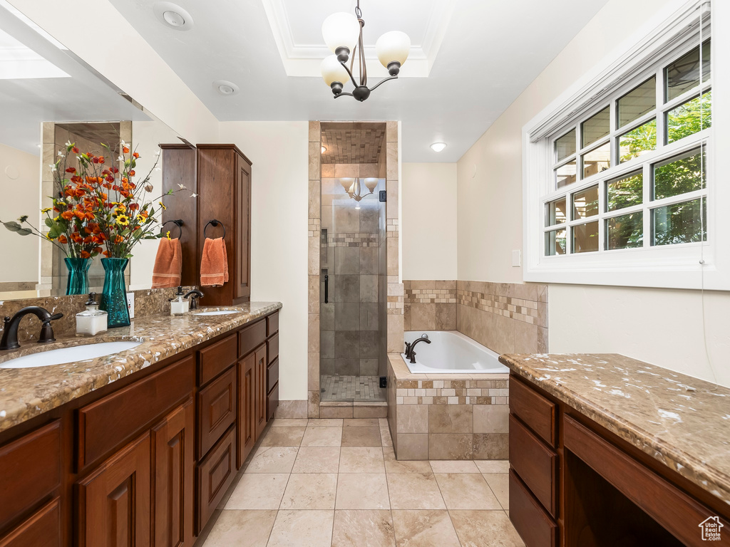 Bathroom featuring tile floors, a raised ceiling, separate shower and tub, and double sink vanity